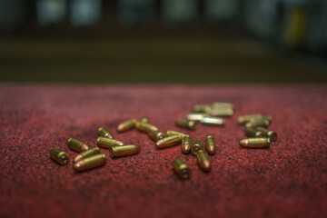 9mm ammunition is placed on a red table inside a shooting range.