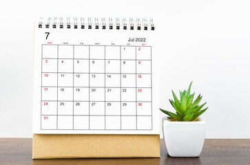 July 2022 desk calendar on wooden background.