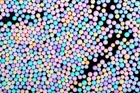 Foam beads of various colors brightly colored on black color background.