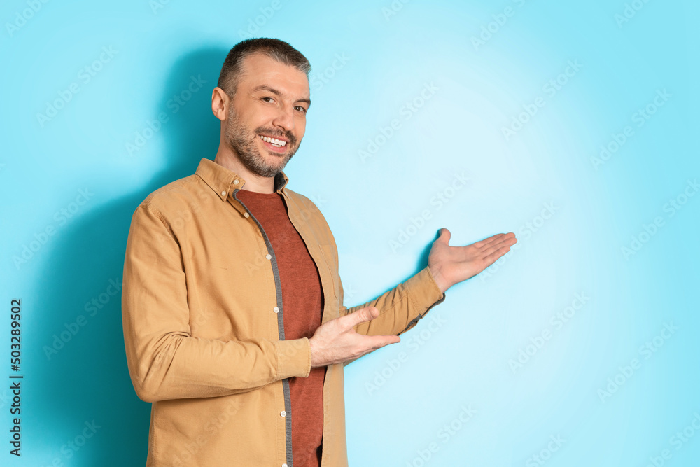 Poster Smiling Middle Aged Man Gesturing Pointing Aside Over Blue Background