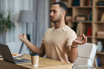 Stress relief at job concept. Calm arab man meditating in front of laptop at home, sitting at workplace