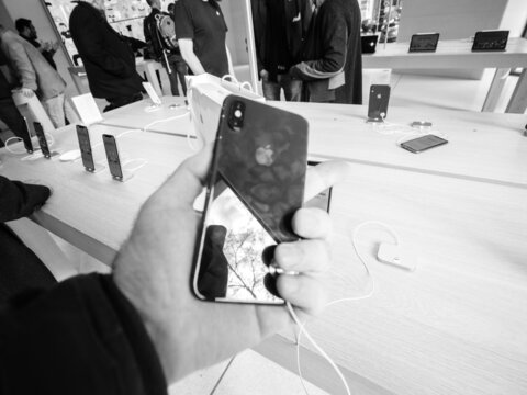 Paris, France - Mar 19 2019: Man POV Personal Perspective Holding IPhone XS Inside The New Apple Store Champs-Elysees - Black And White Defocused Phone