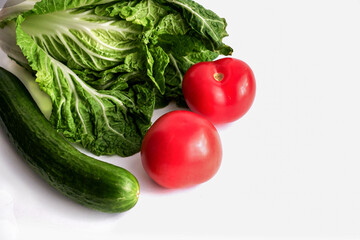 two tomatoes on a white background next to cucumber and cabbage