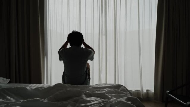 Lonely young man feeling depressed and stressed sitting in the dark bedroom, Negative emotion and mental health concept