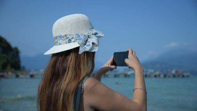 Girl taking pictures at the lake with her smartphone 