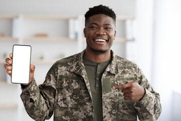 Happy black soldier in military uniform showing his smartphone, mockup