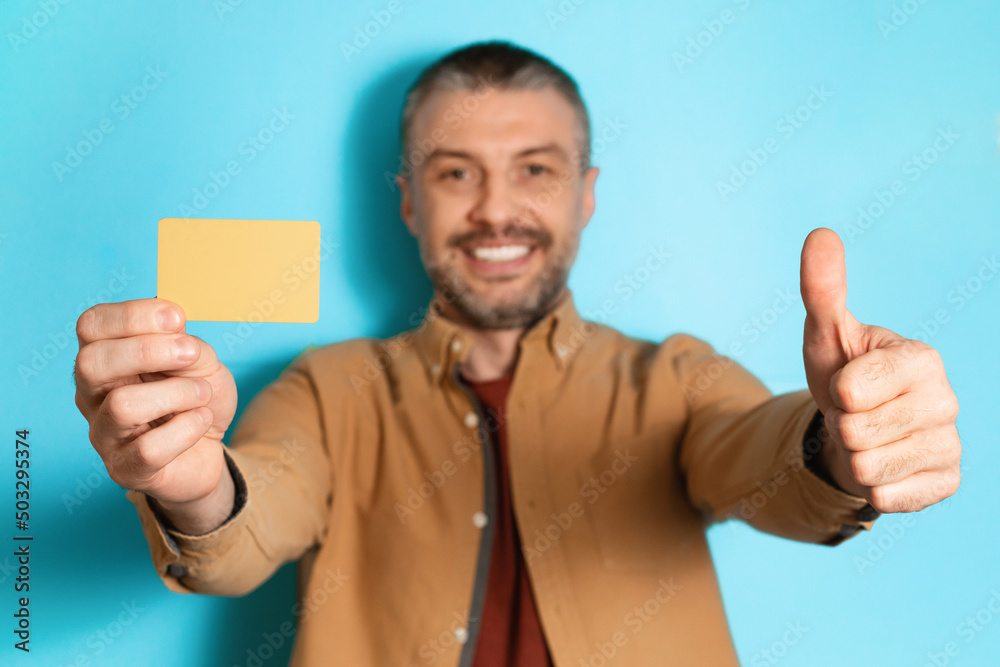 Poster man showing credit card and like standing over blue background