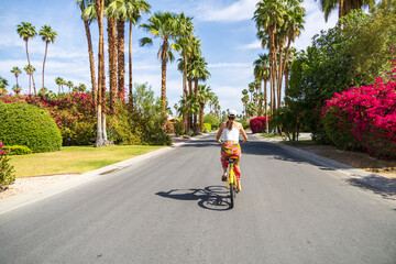 Woman riding a bicycle on a beautiful street with palm trees
