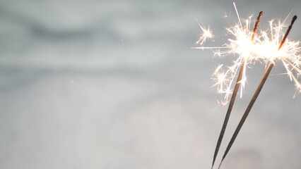 Sparkler firework burning in snow, New Year or Christmas bengal lights. Snowflakes as background. Winter Xmas holiday celebration magic, sparkles glowing, flakes, snowdrift and golden fire stars light