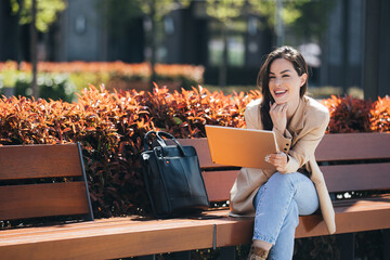 Happy beautiful businesswoman in smart casual using digital tablet outdoors