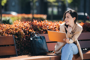 Happy beautiful businesswoman in smart casual using digital tablet outdoors