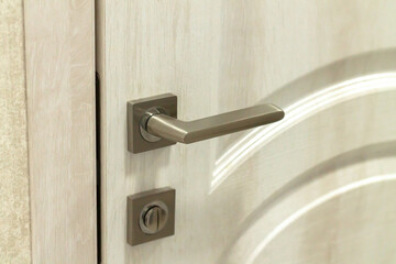 Door handle or doorknob with security lock on wooden background