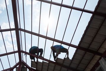 Roofer working on roof structure of building on construction site. Worker install roof tile for new house.