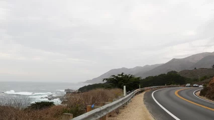 Poster Pacific coast highway 1, Cabrillo road along ocean, foggy California, Big Sur, USA. Coastal road trip, traveling on car by sea. Cloudy misty weather. Yellow dividing line, asphalt. Turn of serpentine. © Dogora Sun