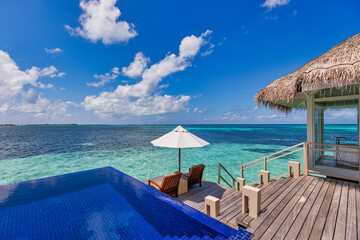 Deck chair with umbrellas at Maldives resort with infinity pool and beach, sea sky view. Luxury...