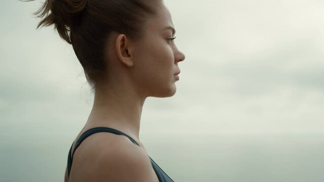 Sporty girl turning face to camera practicing yoga exercise on beach close up.