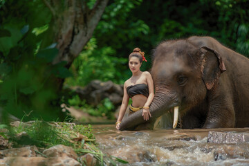 Fototapeta na wymiar Portrait of a woman standing in a river with an elephant, Thailand.