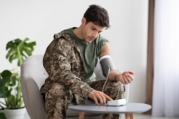 Handsome military man checking blood pressure at home