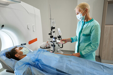 Naklejka na ściany i meble Woman in medical uniform preparing patient for MRI