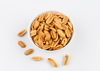 Peeled salted peanuts in white bowl on white background