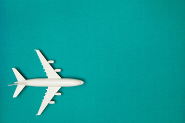 Airplane model. White plane on green background. Travel vacation concept. Summer background. Flat lay, top view, copy space.
