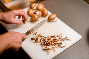 selective focus on sliced champignons and male hand chopping mushrooms with a knife