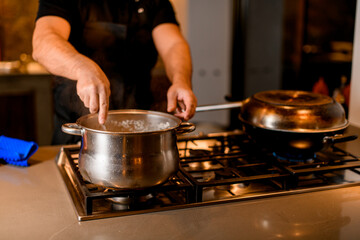 pan on the stove and male chef with a spoon stir the dish in it