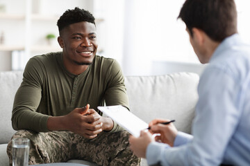 Happy black military man listening to his psychologist - obrazy, fototapety, plakaty