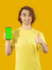 Young man Prep Student with long hair. 20s guy with smartphone on a yellow background