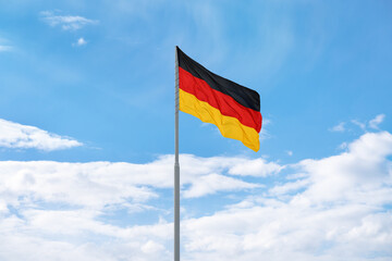 Flag of Germany in front of blue sky and clouds