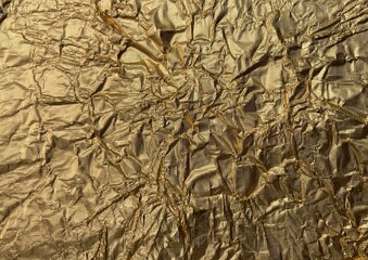 The golden shimmering surface of a metal foil with folds