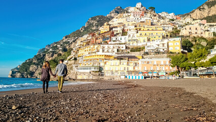 Tourist couple enjoying view on empty Marina Grande Beach and colorful buildings of hillside...