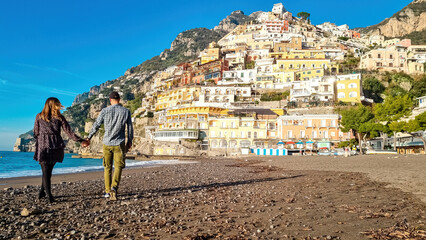 Tourist couple enjoying view on empty Marina Grande Beach and colorful buildings of hillside...