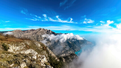 Panoramic view from Monte Comune on coastal town Positano, Praiano appearing from clouds. Magical hiking above fog in Lattari Mountains, Apennines, Amalfi Coast, Campania, Italy, Europe. Misty vibes