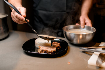 male cook pouring sauce over a slice of fried meat on a plate