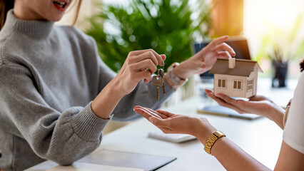 Close-up of real estate agent hand handing key to client at office.