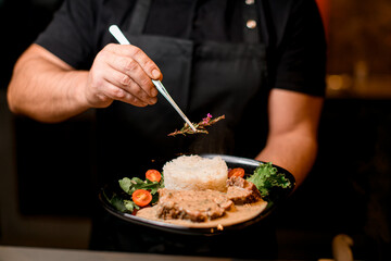 Male hand hold plate of dish and carefully decorate it with a rosemary branch
