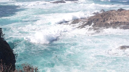 Rocky craggy ocean beach. Big waves crashing on bare cliff, blue water splashing, sea foam. Power of nature near Big Sur, 17-mile drive. Dramatic seascape. Point Lobos, Monterey, California coast, USA