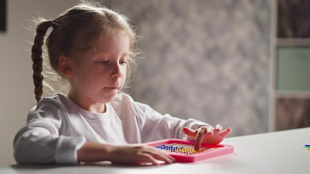 Inspired little girl learn to count with toy abacus at desk