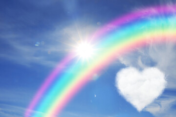 Beautiful view of heart shaped cloud, rainbow and sun in blue sky © New Africa