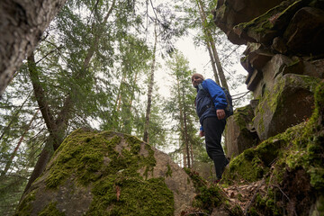 Low angle photo of tourist smiling at camera from rock