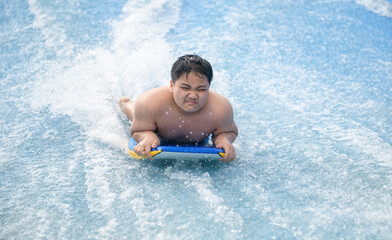 Obese Boy play wave machine on surfboard, recreation and sport