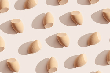 Minimal trend pattern from makeup sponges for foundation cream on beige color background with dark...