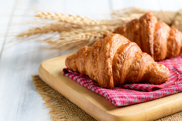 Homemade croissant on wood plate and white wood background, bakery