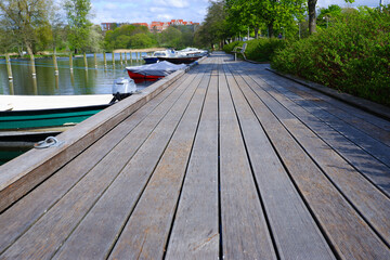 Landscape. Wooden embankment pier for boats on the lake. Place for walking in the city park.