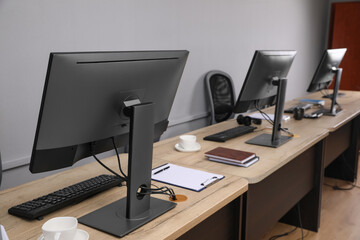 Open office interior. Modern workplaces with computers near light grey wall