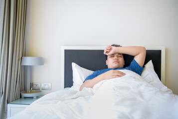 Obraz na płótnie Canvas Sick boy lying in bed with headache in the bedroom, Health care