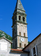 Fototapeta na wymiar Perast town, Montenegro - 16 october 2021 : Clock tower in Perast sailor and fisherman village or town on Adriatic coast, blue sky, stone ancient architecture, middleage cultural heritage