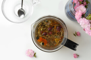 Flat lay composition with freshly brewed tea and beautiful flowers on white table