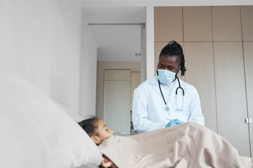 Lying in bed African American girl listens to an adult doctor